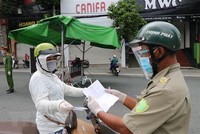 Một người phụ nữ đi chợ trình giấy có giấy tiêm đủ vaccine cho lực lượng kiểm tra trên đường Yersin, thành phố Thủ Dầu Một. (Ảnh: Chí Tưởng/TTXVN).