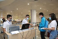 Nhân viên y tế kiểm tra phiếu khai báo y tế của hành khách trước khi làm thủ tục nhập cảnh tại cửa khẩu Sân bay quốc tế Nội Bài (Ảnh: TTXVN).