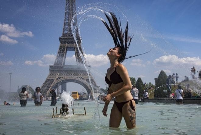 Một cô gái giải nhiệt trước khu vực tháp Eiffel trong đợt nắng nóng cao điểm ở Pháp năm 2019 (Ảnh minh họa: EPA).