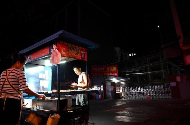 Một người bán đồ ăn trước lối vào một khu công nghiệp ở thành phố Đông Quan, tỉnh Quảng Đông, Trung Quốc - nơi bị ảnh hưởng bởi thiếu điện. Ảnh: AFP