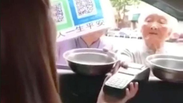 Một bà lão ăn xin người Trung Quốc đang xin tiền bằng máy POS quẹt thẻ ATM. (Nguồn: The Times).