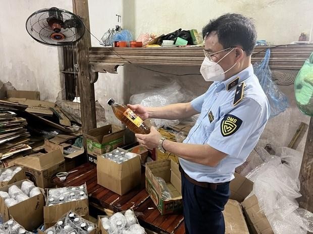 Cán bộ Đội Quản lý thị trường số 24 đang kiểm tra số mật ong vừa tạm giữ tại một cơ sở trên địa bàn huyện Hoài Đức, Hà Nội. (Ảnh: PV/Vietnam+).